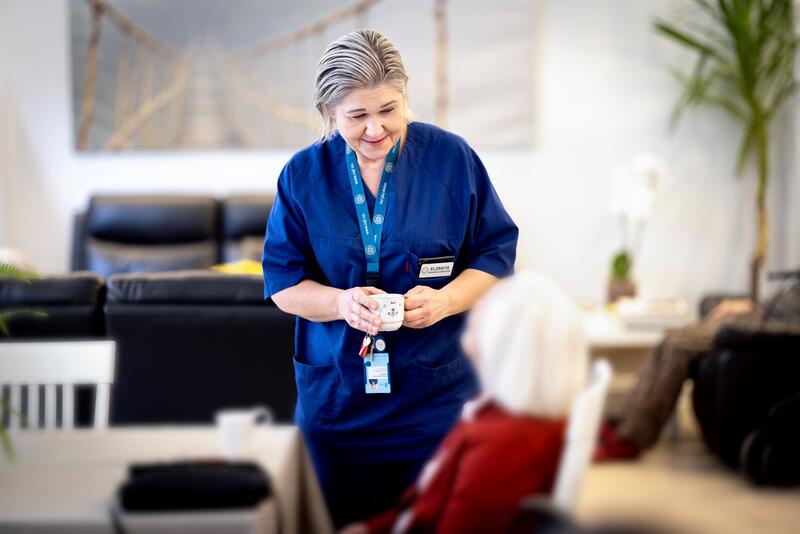 En hjemmesykepleier snakker med en eldre pasient